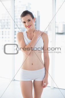 Smiling fit brown haired model in sportswear posing with a hand on the shoulder