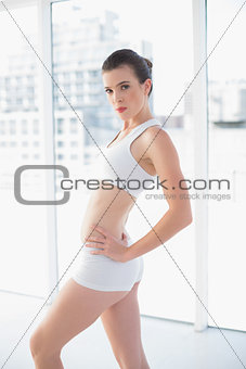 Stern fit brown haired model in sportswear posing with hands on the hips