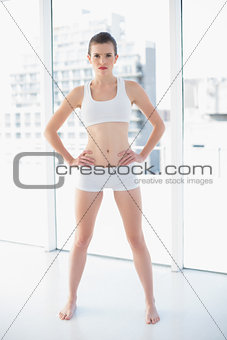 Frowning fit brown haired model in sportswear posing with hands on the hips