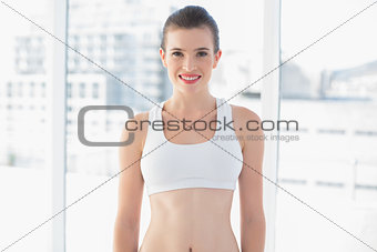 Attractive fit brown haired model in sportswear posing looking at camera