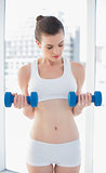 Relaxed fit brown haired model in sportswear exercising with dumbbells