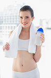 Lovely fit brown haired model in sportswear carrying a towel and a bottle