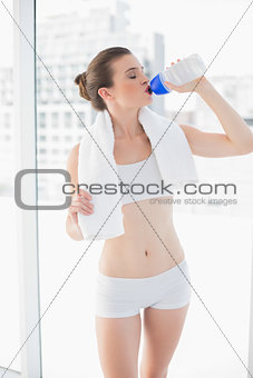Peaceful fit brown haired model in sportswear drinking water