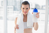 Content fit brown haired model in sportswear carrying a bottle and a towel