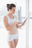 Delighted fit brown haired model in sportswear using a tablet pc
