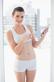 Pleased fit brown haired model in sportswear using a tablet pc