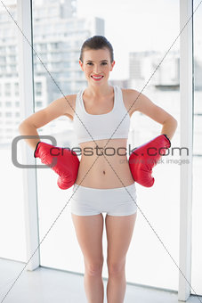 Content fit brown haired model in sportswear wearing boxing gloves
