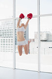 Attractive fit brown haired model in sportswear jumping and wearing boxing gloves