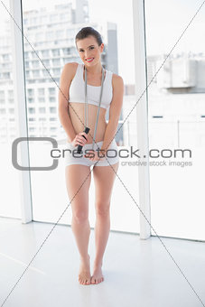 Content fit brown haired model in sportswear playing with a skipping rope
