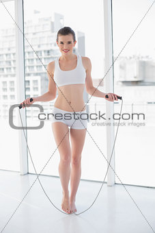 Playful fit brown haired model in sportswear using a skipping rope