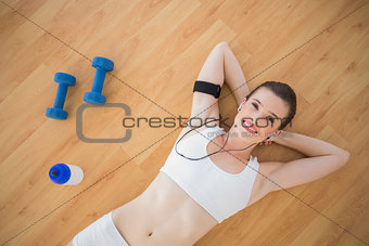 Amused fit brown haired model in sportswear listening to music