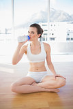 Thoughtful fit brown haired model in sportswear drinking water