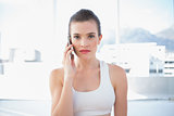 Unsmiling fit brown haired model in sportswear making a phone call