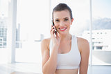 Pleased fit brown haired model in sportswear making a phone call