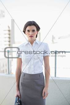 Frowning stylish brown haired businesswoman looking at camera