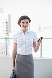 Happy stylish brown haired businesswoman holding a mobile phone