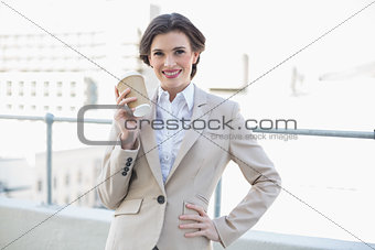 Joyful stylish brown haired businesswoman holding a coffee cup