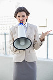 Angry stylish brown haired businesswoman yelling in a megaphone