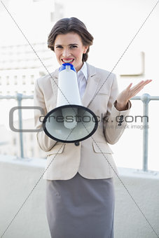 Attractive stylish brown haired businesswoman speaking in a megaphone