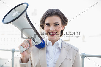 Pleased stylish brown haired businesswoman holding a megaphone