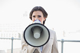 Frowning stylish brown haired businesswoman using a megaphone