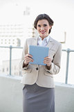 Smiling stylish brown haired businesswoman holding a tablet pc