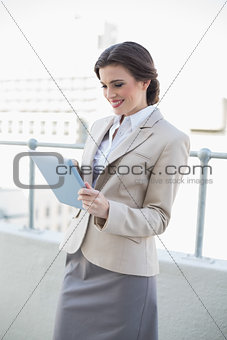Concentrated stylish brown haired businesswoman using a tablet pc