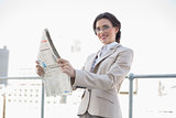 Cheerful stylish brown haired businesswoman reading a newspaper