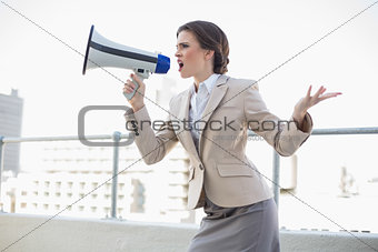Furious stylish brown haired businesswoman shouting in a megaphone