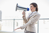 Irritated stylish brown haired businesswoman screaming in a megaphone