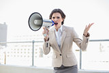 Unhappy stylish brown haired businesswoman screaming in a megaphone
