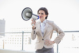 Frowning stylish brown haired businesswoman holding a megaphone