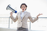 Irritated stylish brown haired businesswoman holding a megaphone