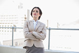 Attractive stylish brown haired businesswoman standing with arms folded