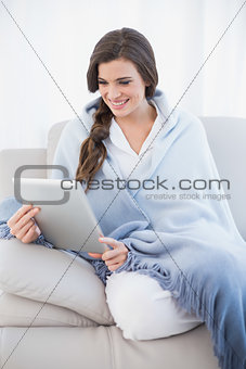 Beautiful casual brown haired woman in white pajamas shopping online with her tablet pc