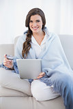 Charming casual brown haired woman in white pajamas shopping online with her tablet pc