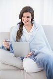 Cute casual brown haired woman in white pajamas shopping online with her tablet pc