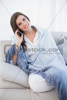 Charming casual brown haired woman in white pajamas making a phone call