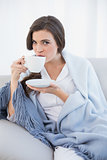 Peaceful casual brown haired woman in white pajamas drinking coffee