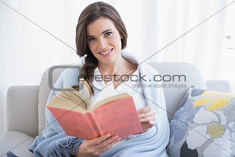 Pretty casual brown haired woman in white pajamas reading a book