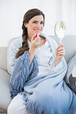 Smiling casual brown haired woman in white pajamas applying gloss