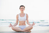 Peaceful slim brown haired model in white sportswear meditating in lotus position