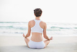 Gorgeous slim brown haired model in white sportswear meditating in lotus position