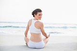 Content slim brown haired model in white sportswear meditating in lotus position