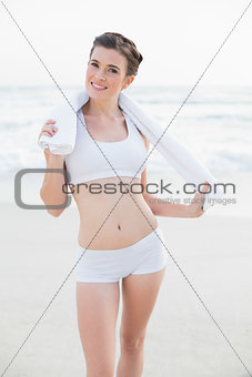Amused slim brown haired model in white sportswear holding a towel