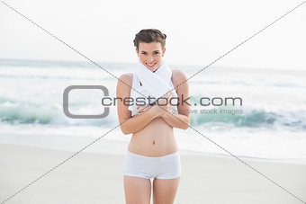 Content slim brown haired model in white sportswear wearing a towel