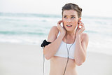 Surprised slim brown haired model in white sportswear listening to music