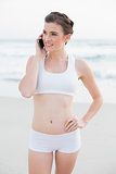Thoughtful slim brown haired model in white sportswear making a phone call