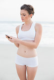 Charming slim brown haired model in white sportswear using her mobile phone