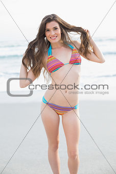 Gorgeous slim brown haired model in coloured bikini holding her hair
